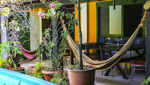 Un patio con plantas en macetas, una hamaca y mobiliario exterior.