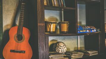 A guitar leaning against a wall, a shelf with books, and a soccer ball.