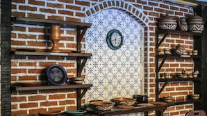 Una cocina rústica con paredes de ladrillo, repisas con cerámica y un reloj.