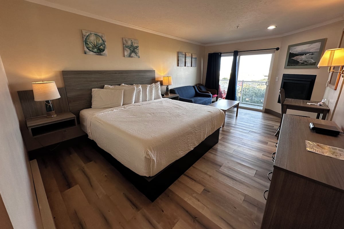 A hotel room with a large bed, a desk, a chair, and a TV.