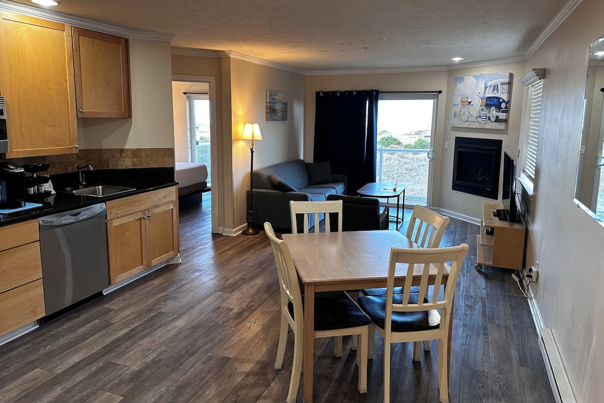 A compact living space with a kitchenette, a dining area with a table and chairs, a sofa, and a television.