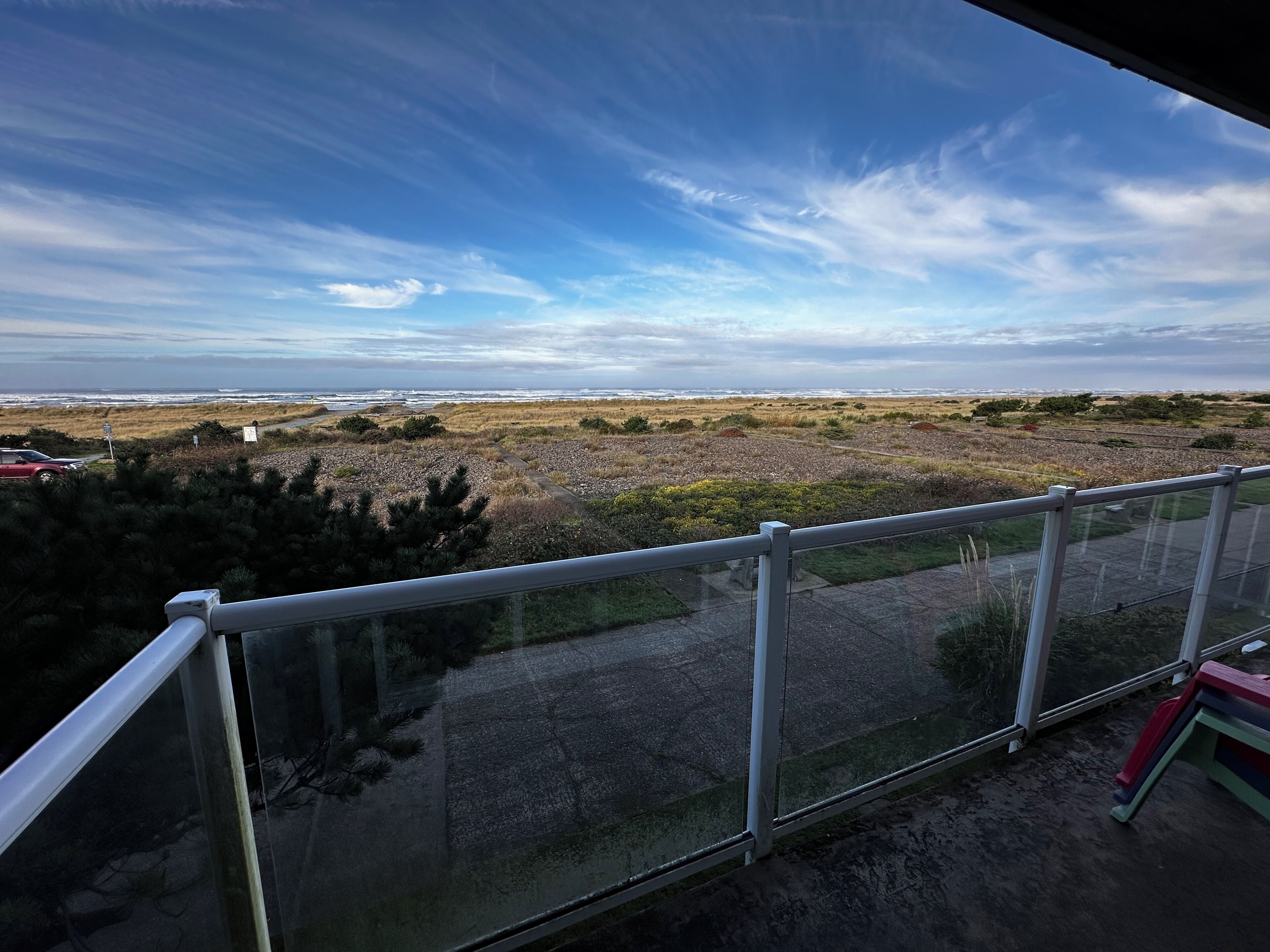Uma varanda com vista para a paisagem costeira, incluindo uma praia e o oceano.