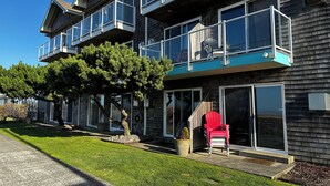 A multi-story residential building with balconies, large windows, and a well-maintained lawn.