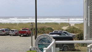 A view of the oceanfront with parked cars and a sign indicating the location.