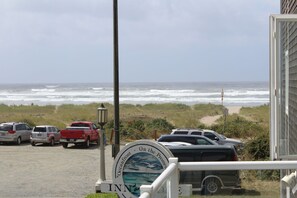 A view of the oceanfront with parked cars and a sign indicating the location.
