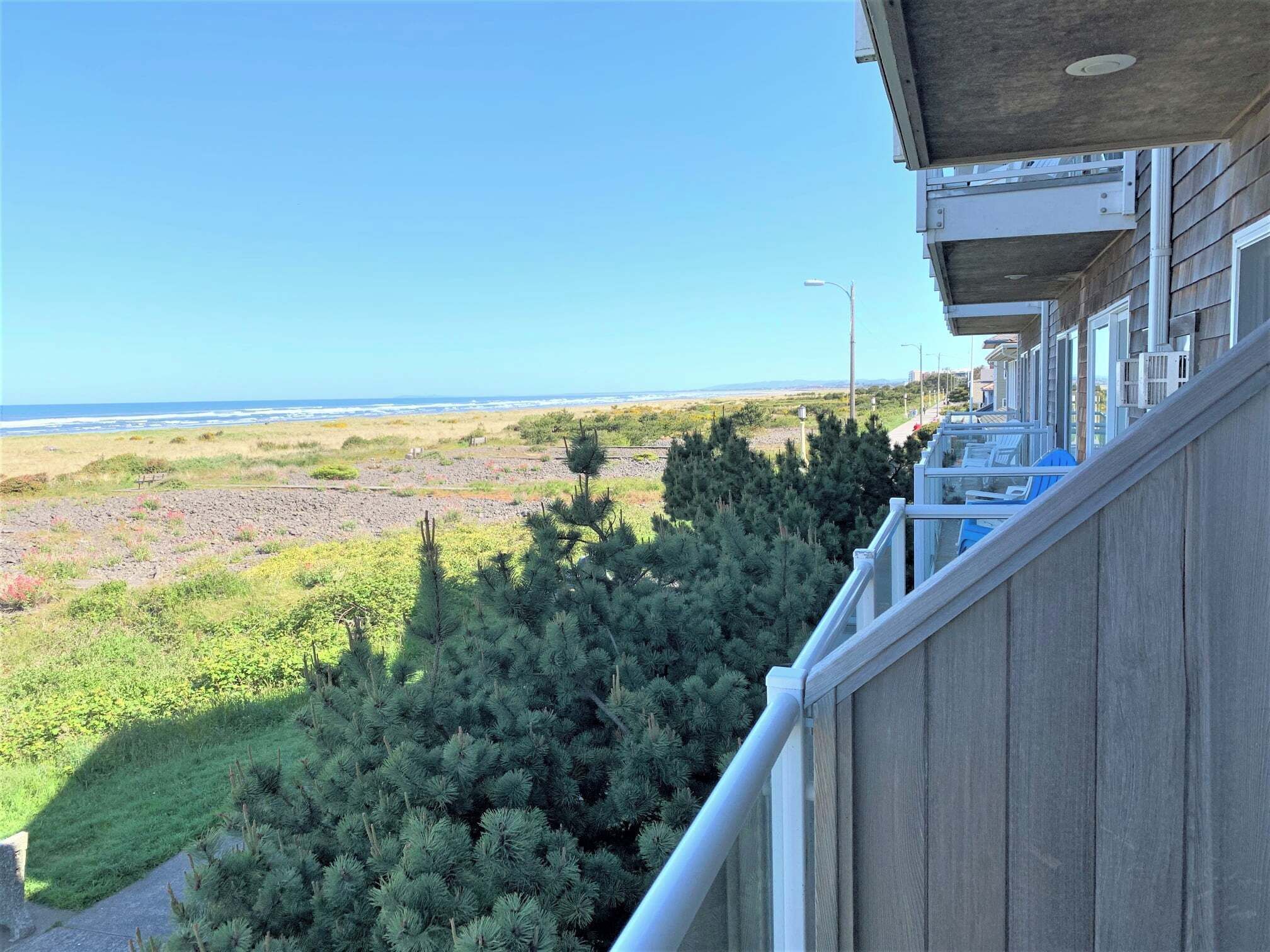 A balcony with a view of the beach and dunes.