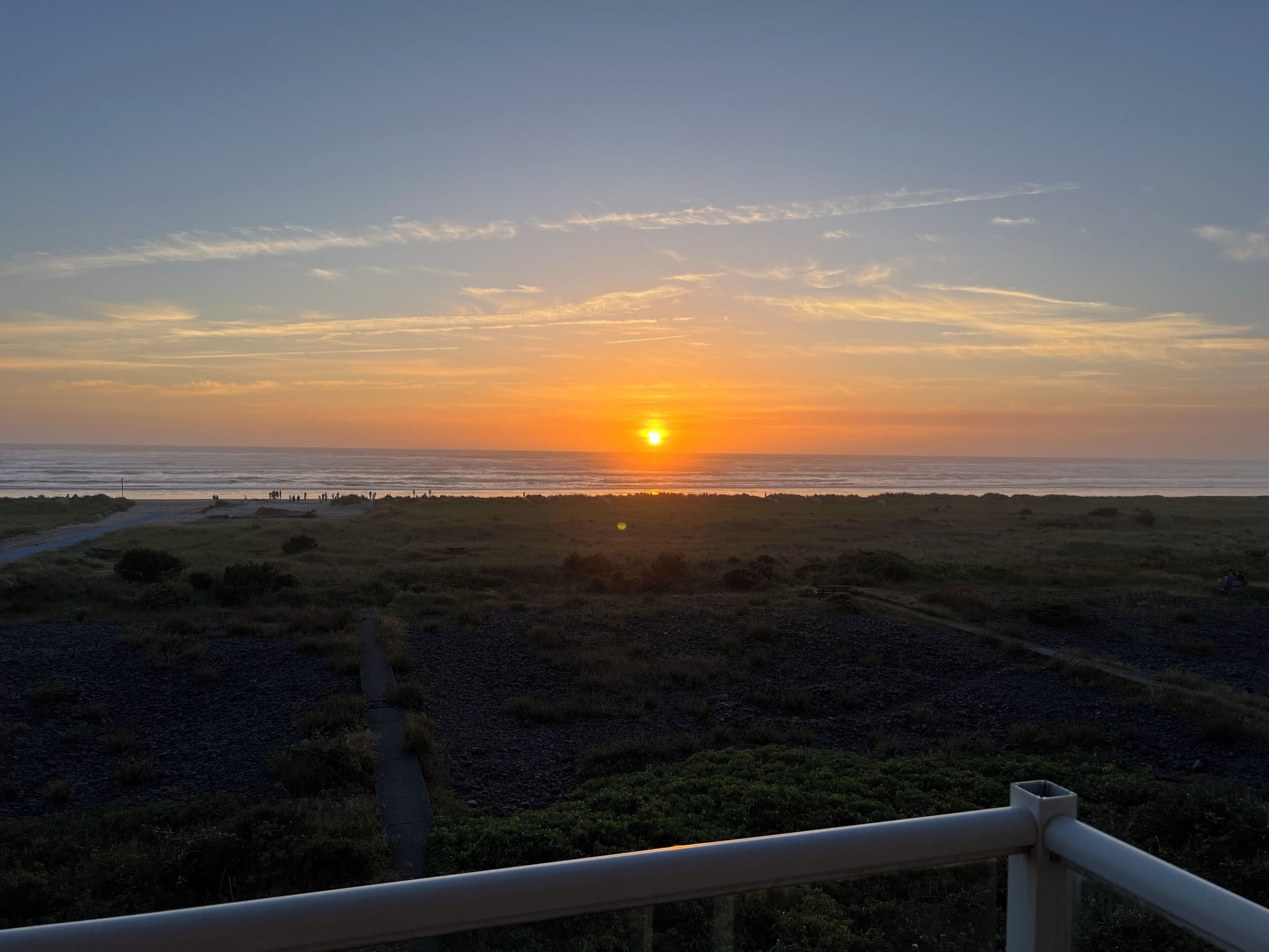 Atardecer sobre una playa con un camino que lleva al agua.