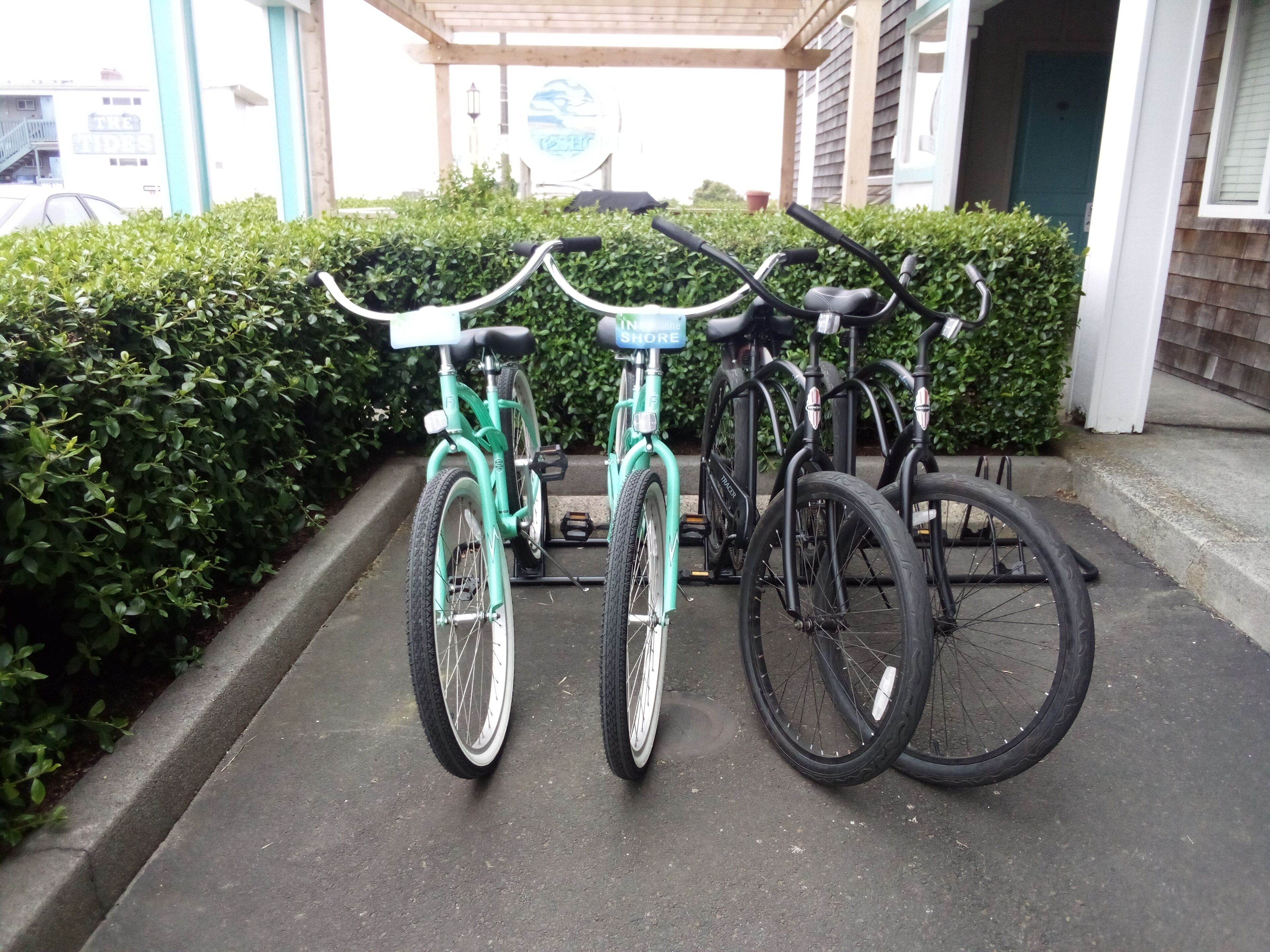 A row of bicycles parked in a covered area with a building in the background.