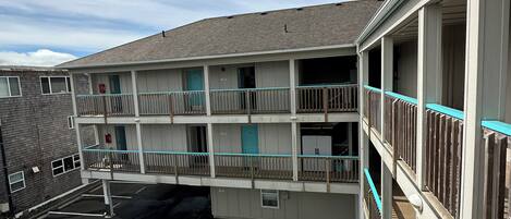 Un motel à plusieurs étages avec un parking, un VUS blanc garé sur le parking et un escalier menant aux étages supérieurs.