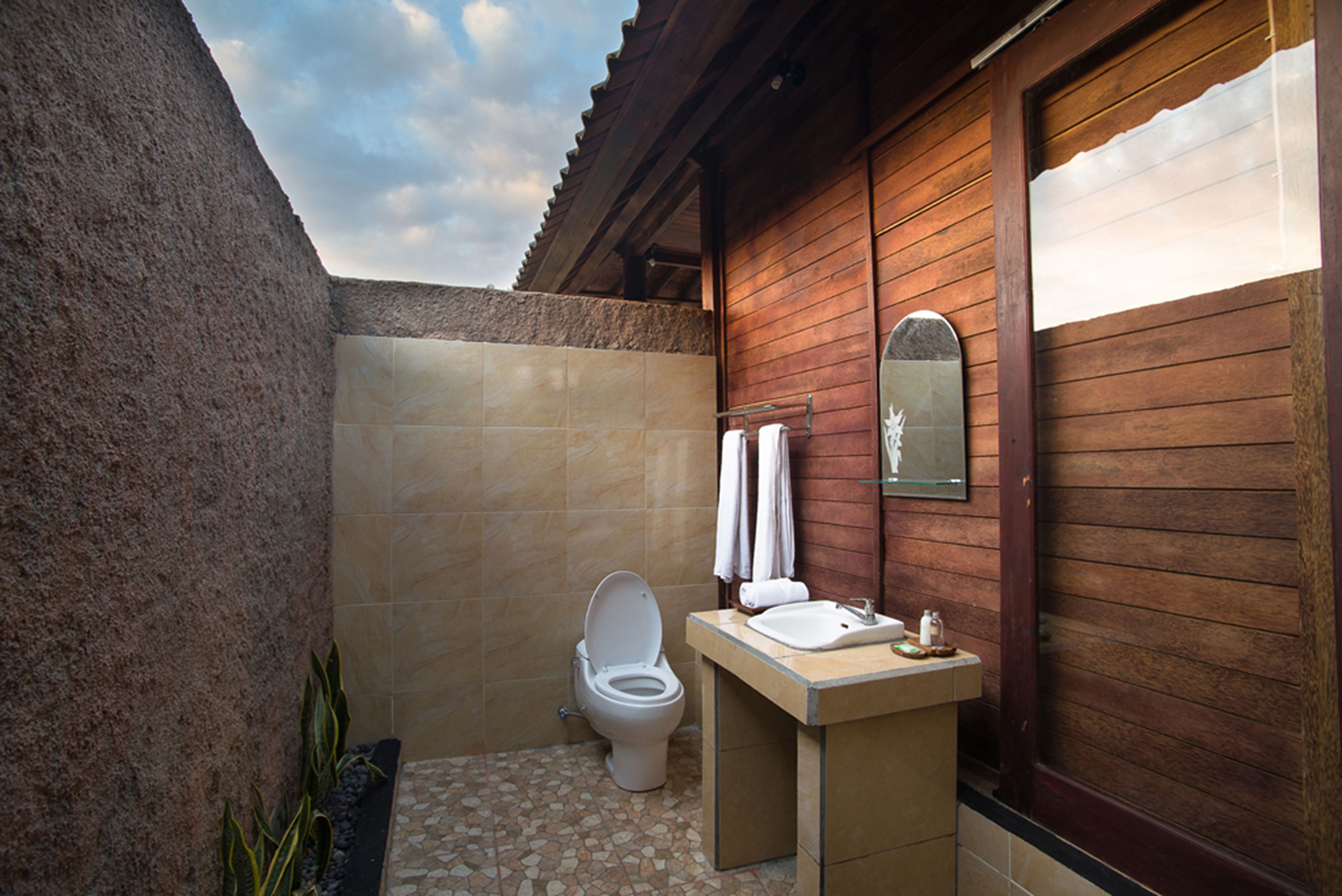 Une salle de bain avec des toilettes, un lavabo et des murs en bois.