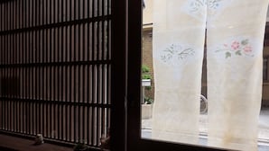 Una ventana con una celosía de madera y una cortina de estampado floral.