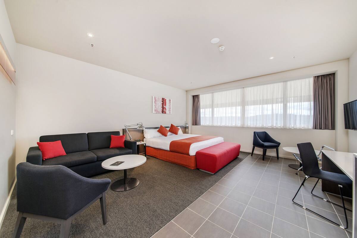 Una habitación de hotel moderna con sofá, cama, escritorio y una silla.