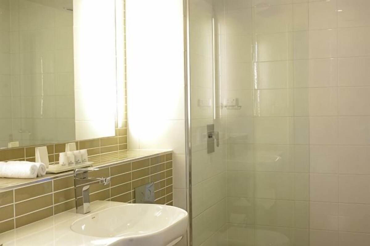 A bathroom with a sink, mirror, and shower.