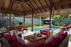 Área externa coberta com piscina, assentos e uma mesa com cadeiras.