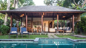 A covered outdoor area with a pool, lounge chairs, and a dining setup. - Mango Tree Villas (Jimbaran)