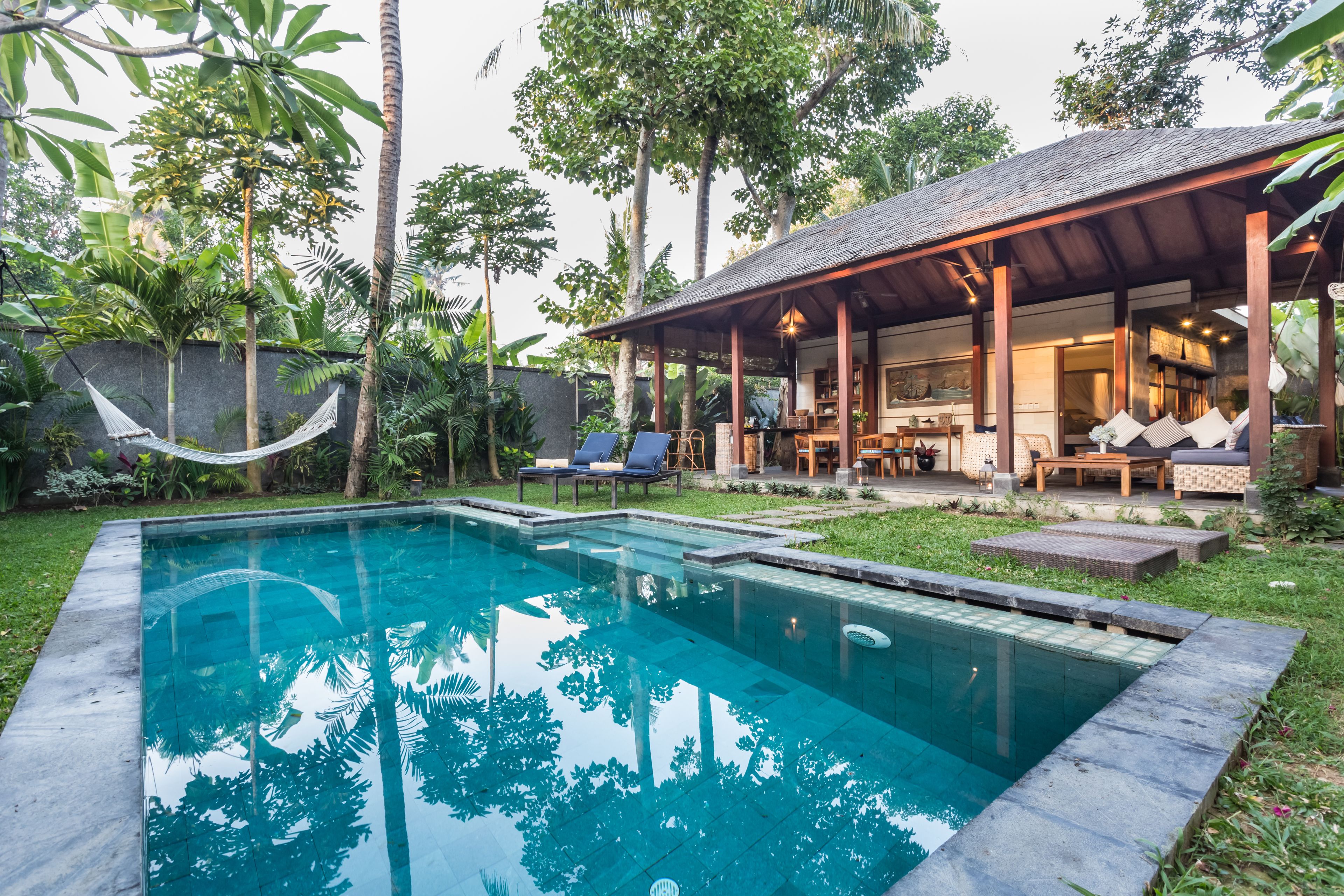 A poolside area with a covered seating area, lounge chairs, and a hammock.