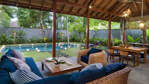 Un espacio exterior cubierto con piscina, sillas de descanso y una mesa de comedor.