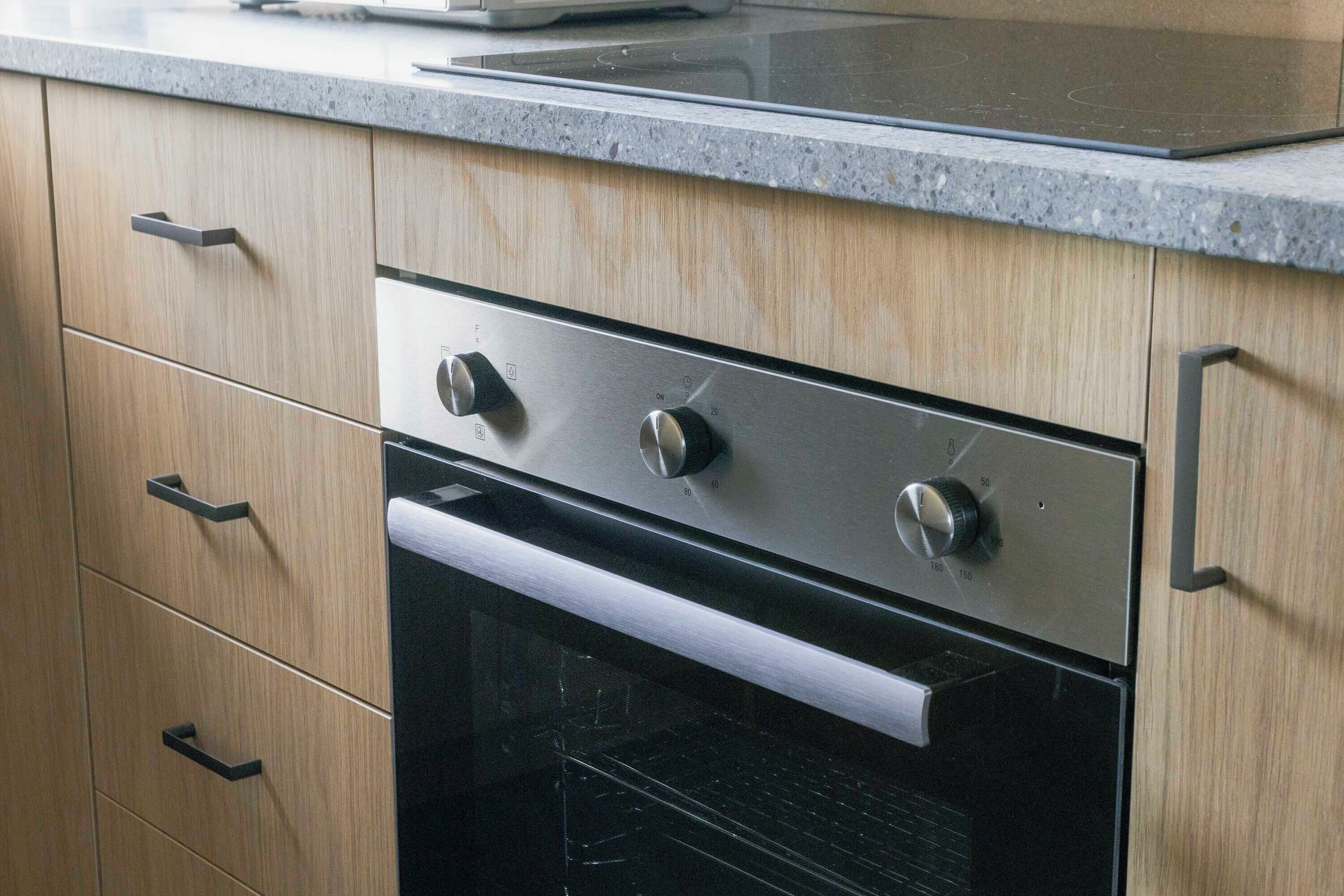 Una cucina moderna con mobili in legno, un forno in acciaio inossidabile e un piano di lavoro in granito.
