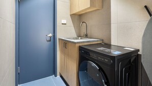 A compact laundry room with a washing machine, a sink, and wooden cabinets. - Hotel Jesmond (Jesmond)