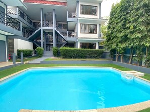 Un edificio residencial con piscina, escaleras y césped bien cuidado.