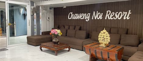 Een moderne woonkamer met een bank, twee salontafels en een decoratieve wand.