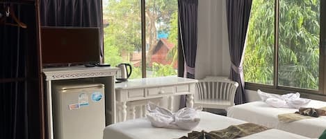 A hotel room with two beds, a desk, a refrigerator, and a window with curtains.