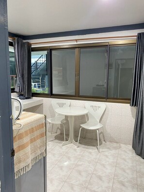 A small dining area with a round table and four chairs, a window with curtains, and a tiled floor. - Chaweng Noi Resort (Koh Samui)