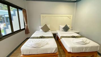 Habitación de hotel con dos camas individuales, piso de madera, ventana con cortinas y vistas al exterior.