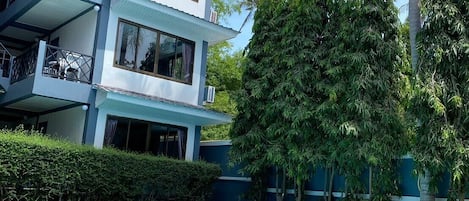 Un hotel a più piani con piscina, immerso nel verde e palme.