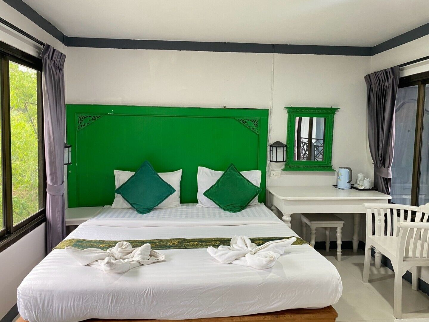 A hotel room with a bed, a desk, a chair, and a window.