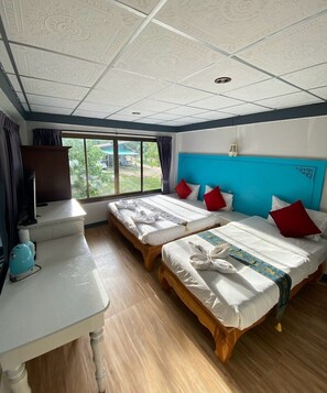 A hotel room with two beds, a desk, a television, and a view of greenery outside. - Chaweng Noi Resort (Koh Samui)