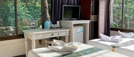 A hotel room with a bed, a desk with a television, and large windows.