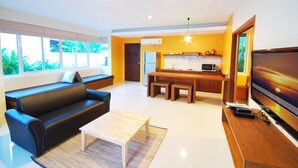 A modern living room with a sofa, coffee table, and TV. - The Living Pool Villas (Koh Samui)