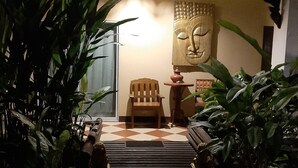 Un rincón interior acogedor con un banco de madera, una mesa pequeña y una estatua de Buda.