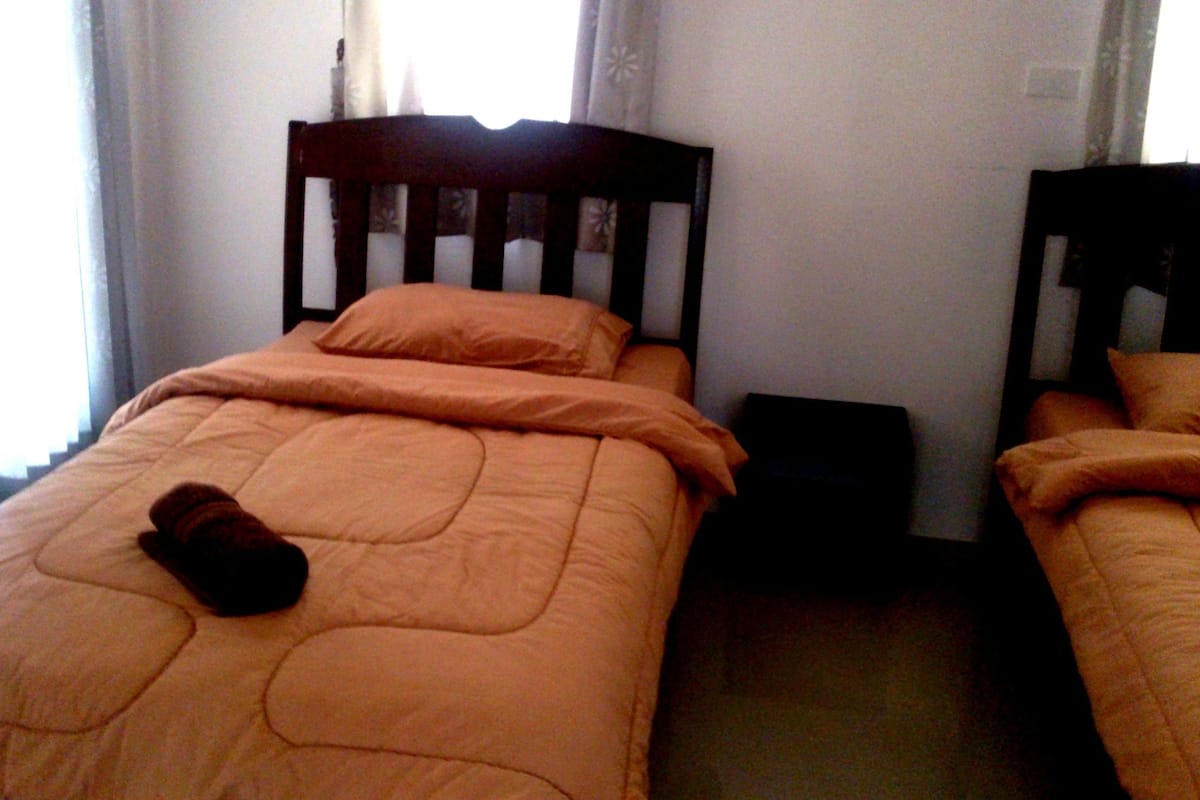 A single bed with an orange bedspread and a brown sock on it.