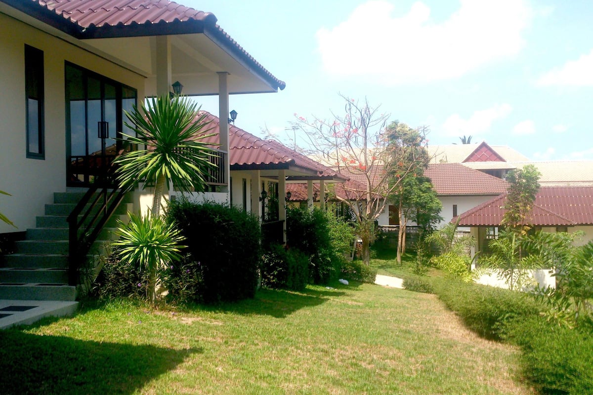 A house with a red-tiled roof, a covered porch, and a well-maintained lawn.