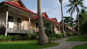 A row of bungalow-style buildings with red roofs, surrounded by lush greenery and palm trees. - Thong Takian Resort (Koh Samui)