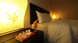 A hotel room with a bed, a bedside table with a drink and a book, and a wall-mounted lamp. - Thong Takian Resort (Koh Samui)