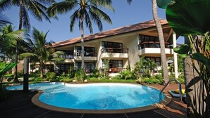 A hotel with a swimming pool surrounded by palm trees and tropical plants. - Thong Takian Resort (Koh Samui)
