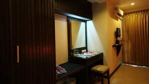 A hotel room with a wooden wardrobe, a desk with a mirror, a chair, a small trash bin, and a television on the wall. - Thong Takian Resort (Koh Samui)
