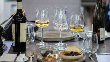 Une table à manger dressée avec des verres à vin, des assiettes, des couverts et une bouteille de vin.
