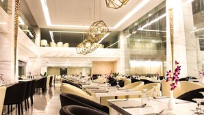 A spacious hotel dining area with multiple tables and chairs, modern lighting fixtures, and a view of the lobby. - Sokhalay Angkor Residence and Spa (Siem Reap)