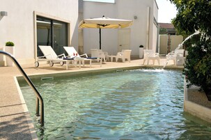 Una piscina al aire libre, sillones reclinables de piscina