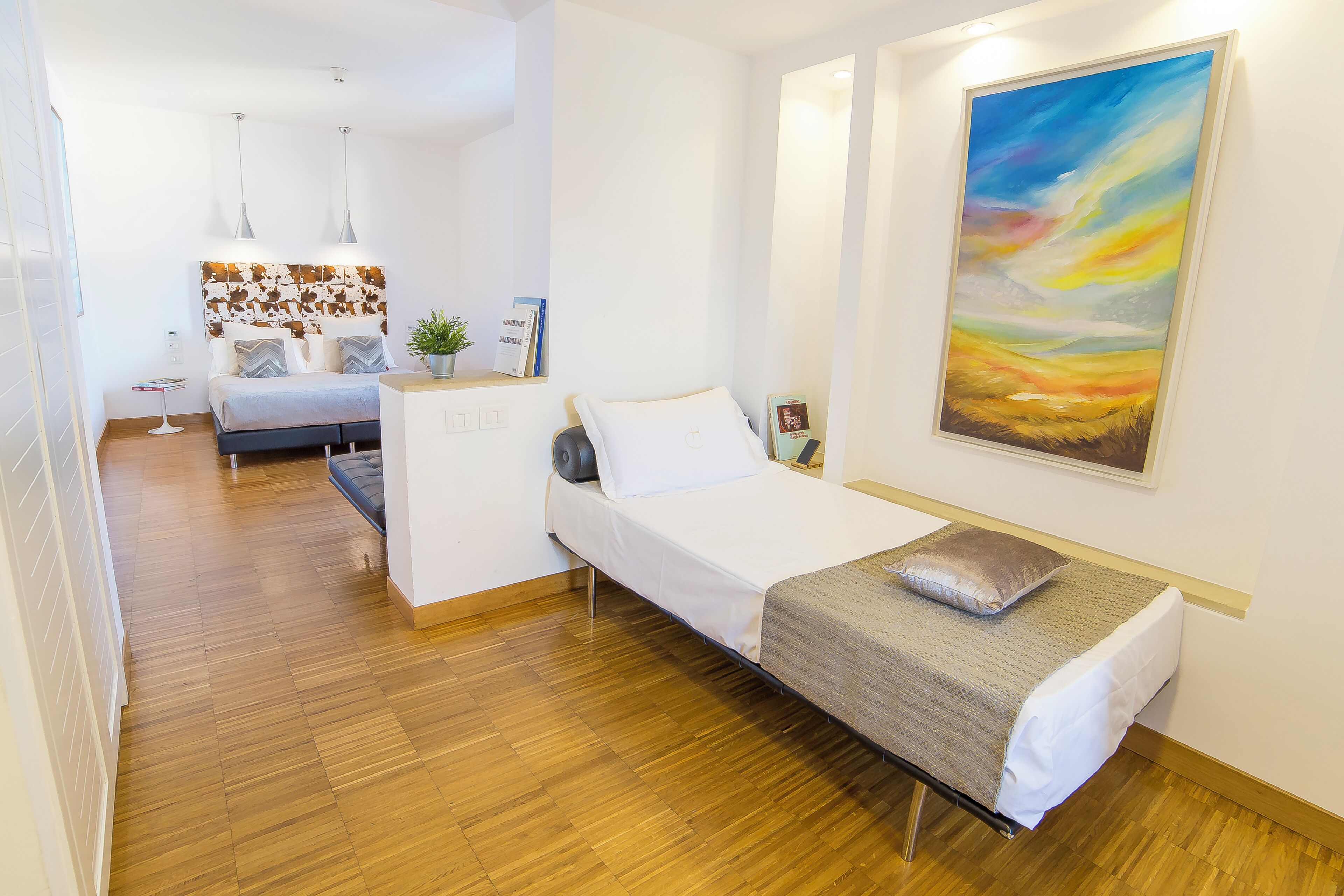 Una habitación de hotel con cama, mesita de noche, decoración en la pared y un pequeño escritorio.