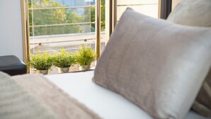 A window with metal bars, a sofa with a cushion, and two potted plants on the windowsill. - Hotel del Conte (Fondi)