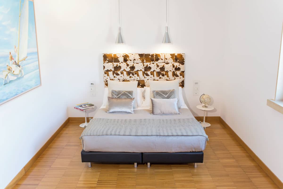 A bedroom with a bed, two bedside tables, a globe, and a painting on the wall.
