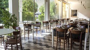 A restaurant with hexagonal patterned flooring, wooden tables and chairs, and large windows with blinds. - Hotel del Conte (Fondi)