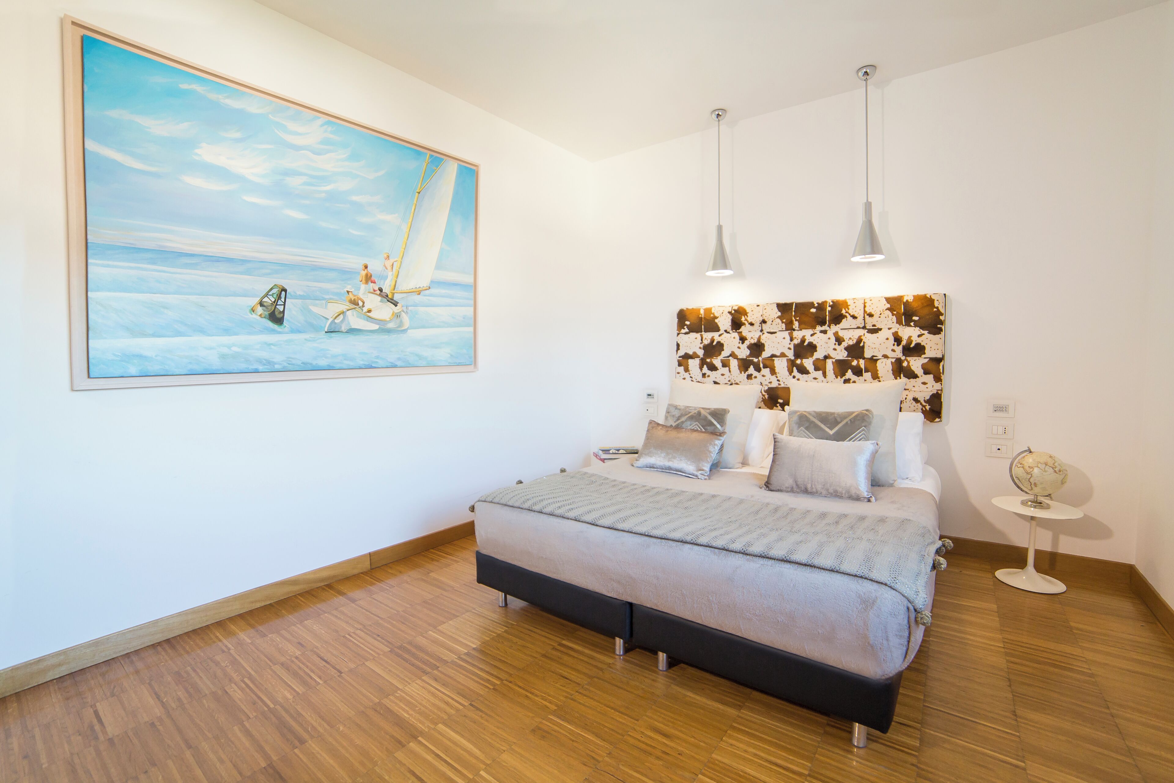 Un dormitorio con cama, un cuadro, un globo terráqueo y un cabecero de diseño original.