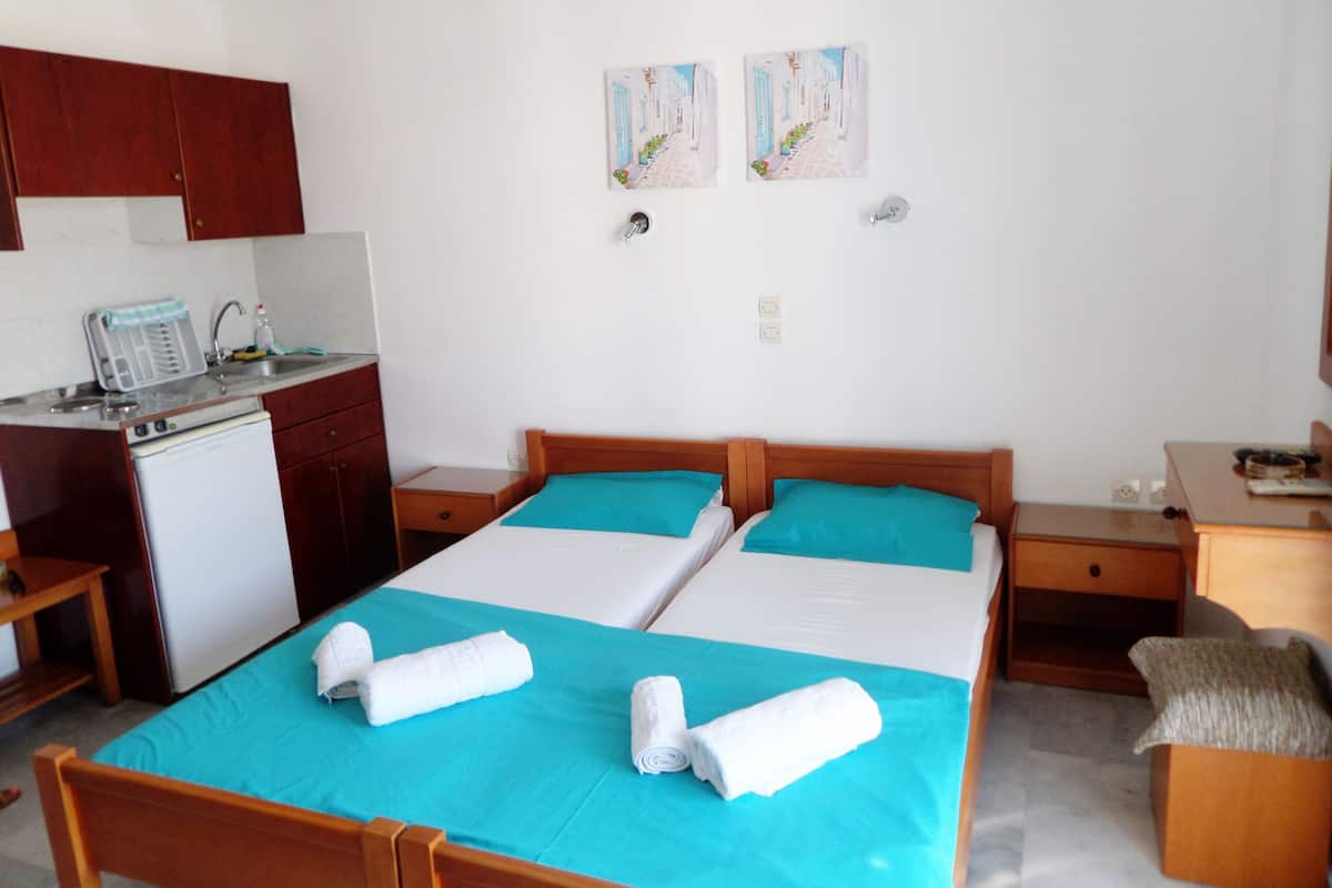 Ett hotellrum med två sängar, ett litet kök och två tavlor som hänger på väggen.