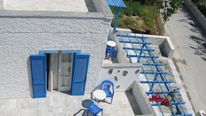 A rooftop terrace with blue shutters, a small table, and chairs. - Hotel Rea (Naxos)